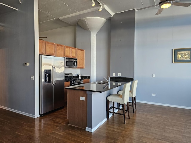 kitchen featuring dark hardwood / wood-style flooring, a kitchen bar, sink, and appliances with stainless steel finishes