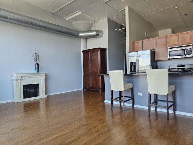 kitchen with a kitchen breakfast bar, kitchen peninsula, dark wood-type flooring, and stainless steel appliances