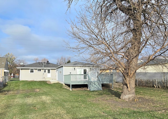 rear view of house with a wooden deck and a lawn