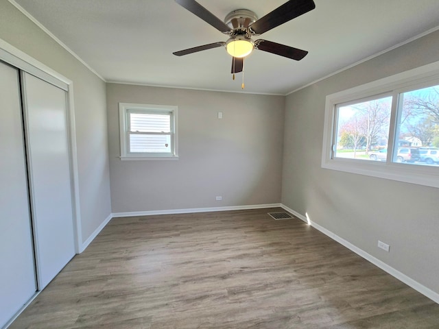 unfurnished bedroom featuring ceiling fan, a closet, ornamental molding, and light hardwood / wood-style flooring