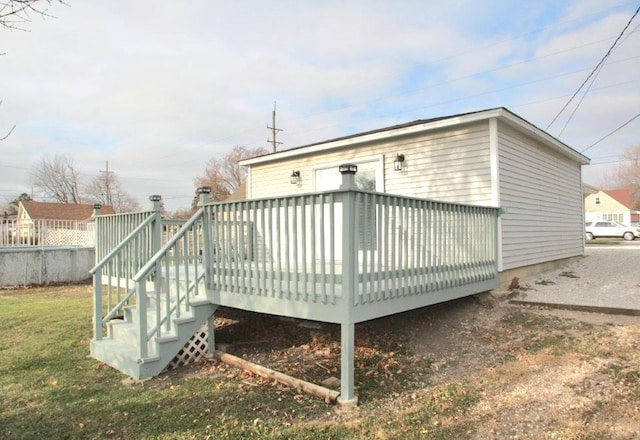 back of property featuring a wooden deck and a lawn