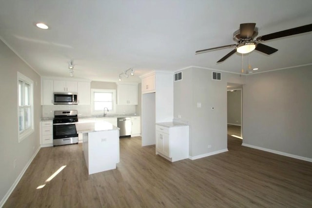 kitchen featuring sink, hardwood / wood-style flooring, stainless steel appliances, a center island, and white cabinets