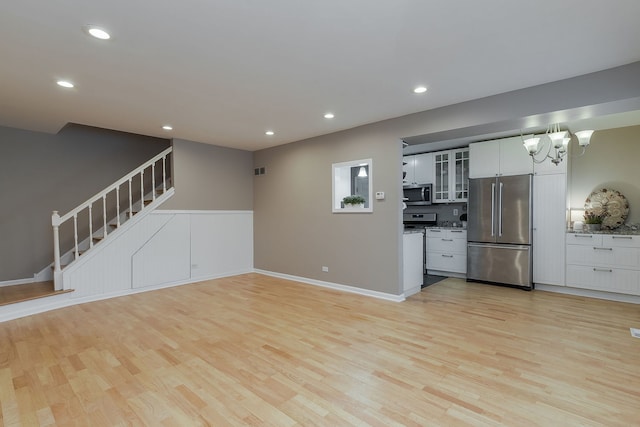 unfurnished living room featuring light hardwood / wood-style floors and an inviting chandelier