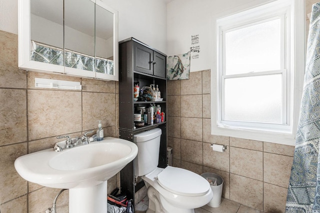 bathroom featuring toilet, tile walls, and sink