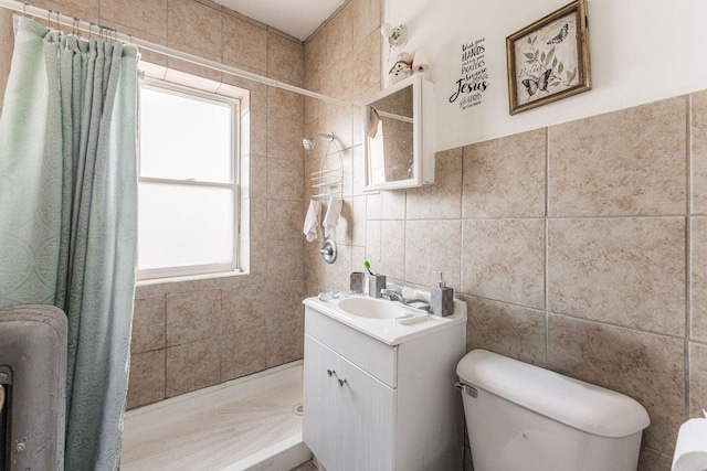 bathroom with walk in shower, vanity, toilet, and tile walls