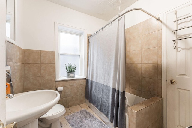 bathroom with tile patterned flooring, toilet, sink, and tile walls