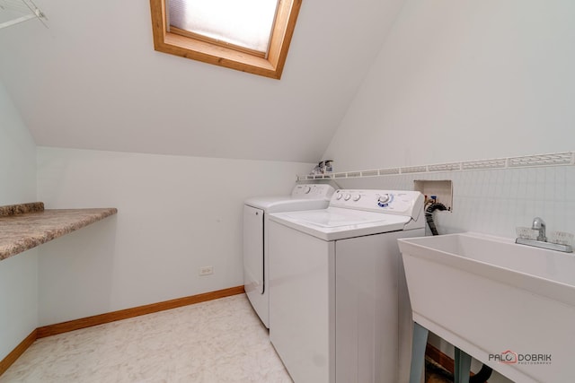 clothes washing area featuring a skylight, sink, and washing machine and clothes dryer