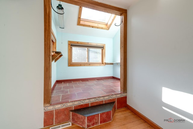 interior space featuring hardwood / wood-style flooring and lofted ceiling with skylight