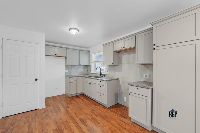 kitchen with decorative backsplash, light hardwood / wood-style floors, gray cabinets, and sink