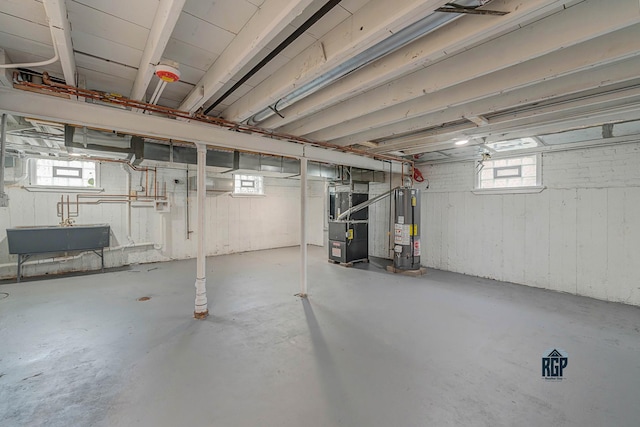 basement featuring heating unit, a healthy amount of sunlight, sink, and water heater