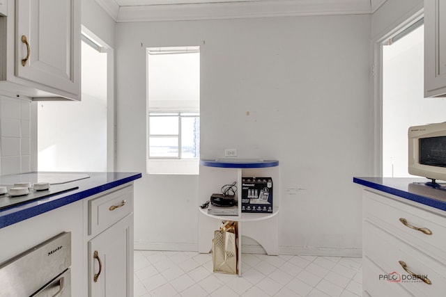 kitchen with white cabinetry, wall oven, ornamental molding, and white cooktop