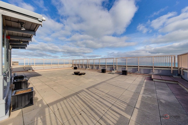 view of patio with a water view and a fire pit