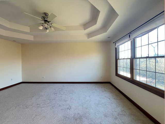 carpeted empty room featuring a raised ceiling and ceiling fan