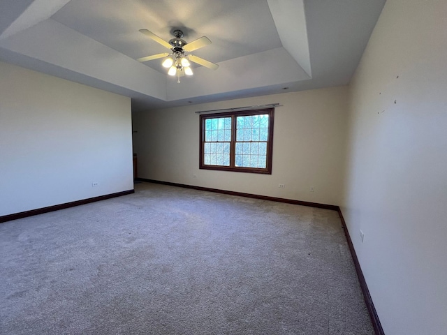 carpeted empty room with ceiling fan and a tray ceiling