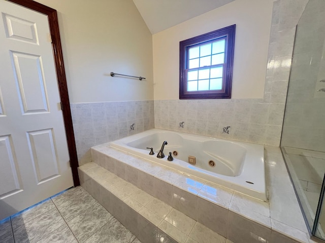 bathroom with tile patterned floors, lofted ceiling, and tiled bath