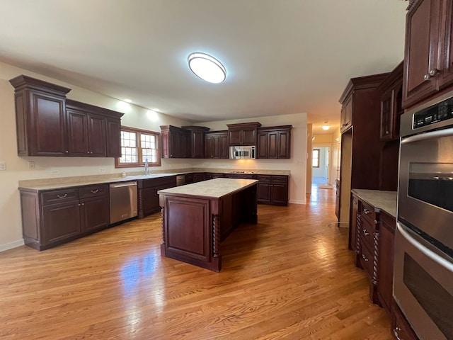 kitchen featuring appliances with stainless steel finishes, dark brown cabinetry, sink, a center island, and light hardwood / wood-style floors