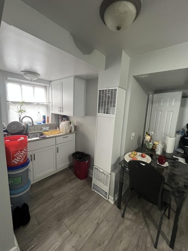 kitchen featuring wood-type flooring, white cabinetry, and sink