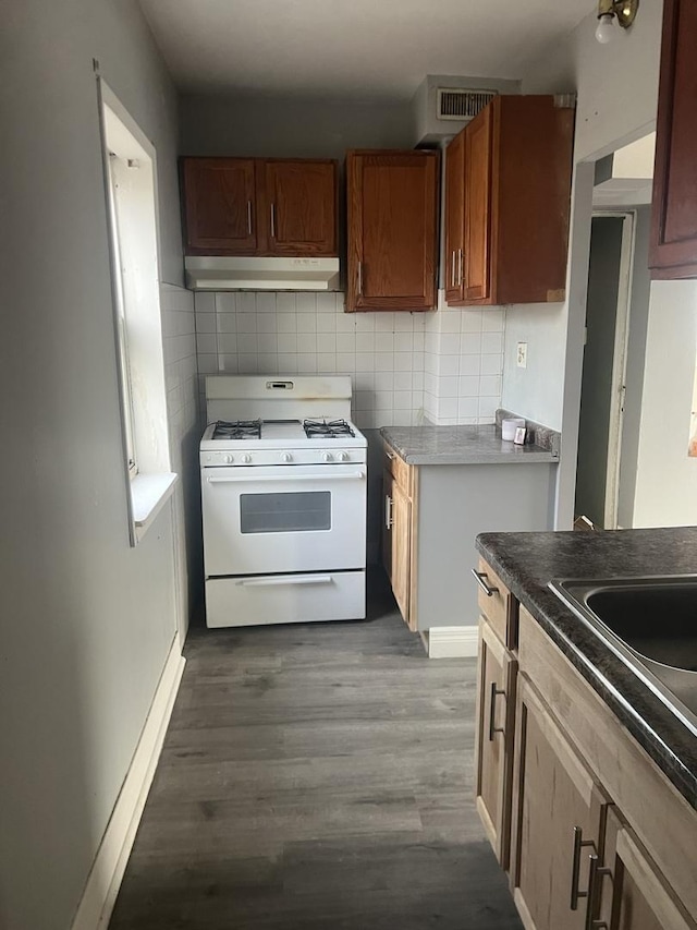 kitchen featuring hardwood / wood-style floors, white range with gas stovetop, and tasteful backsplash