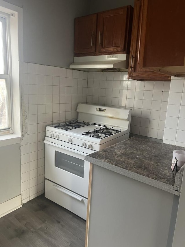 kitchen featuring dark wood-type flooring, white range with gas cooktop, and tile walls