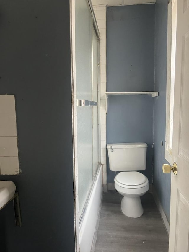 bathroom featuring shower / bath combination with glass door, toilet, and hardwood / wood-style flooring