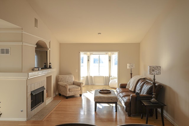 living room with light wood-type flooring, a fireplace, and high vaulted ceiling