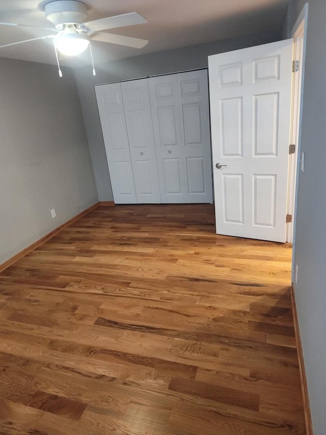 unfurnished bedroom with hardwood / wood-style flooring, ceiling fan, and a closet