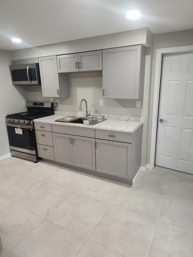 kitchen featuring gray cabinetry, sink, light tile patterned flooring, and stainless steel appliances