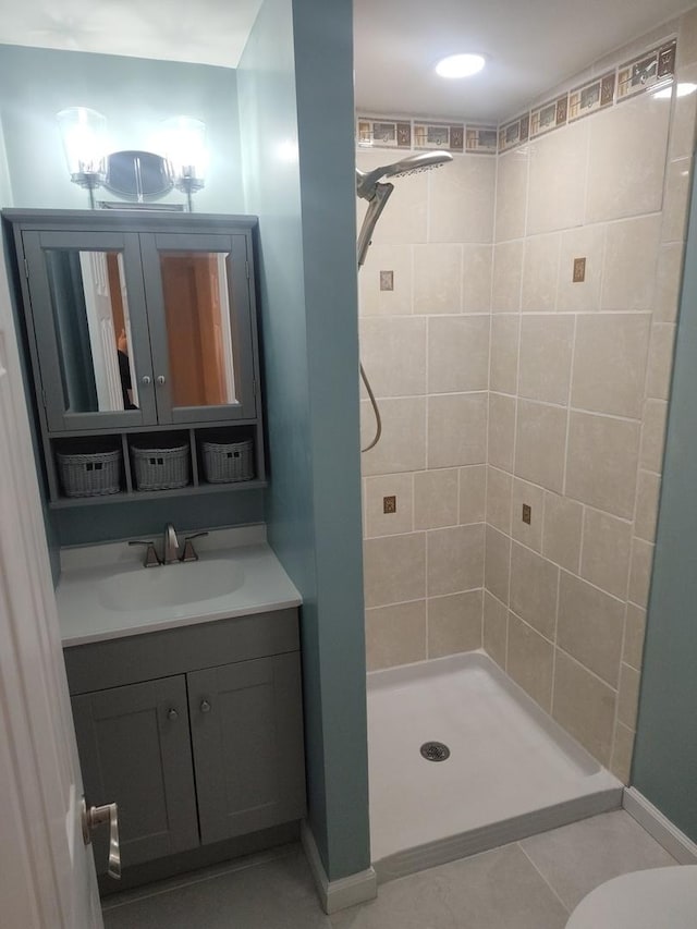 bathroom featuring a tile shower, tile patterned flooring, vanity, and toilet