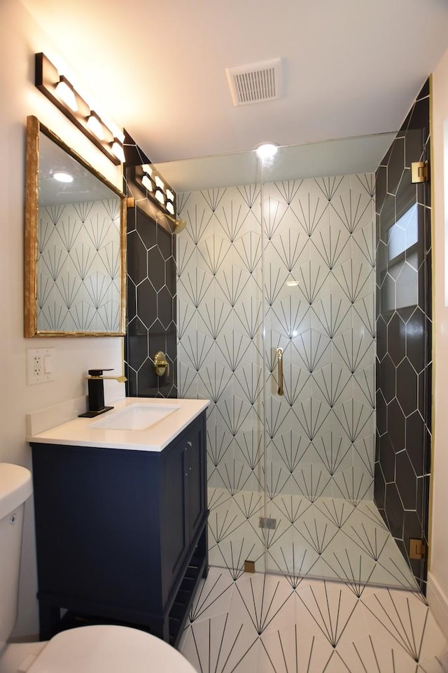 bathroom featuring vanity, tile patterned floors, toilet, tile walls, and an enclosed shower