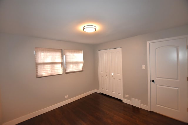 unfurnished bedroom featuring dark hardwood / wood-style floors and a closet