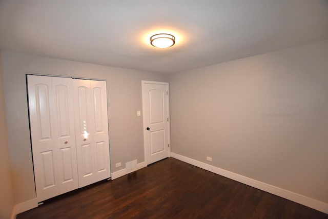 unfurnished bedroom with dark wood-type flooring and a closet