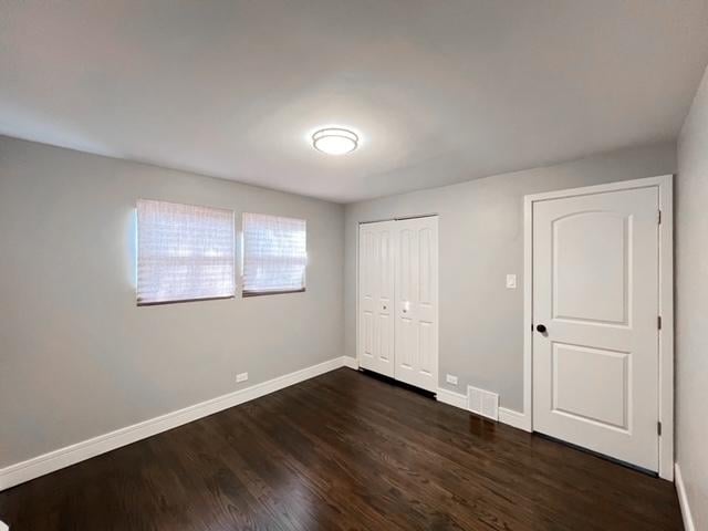 unfurnished bedroom with dark hardwood / wood-style flooring and a closet