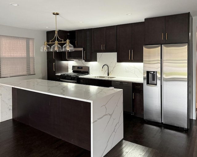 kitchen featuring light stone countertops, sink, dark hardwood / wood-style flooring, decorative light fixtures, and appliances with stainless steel finishes