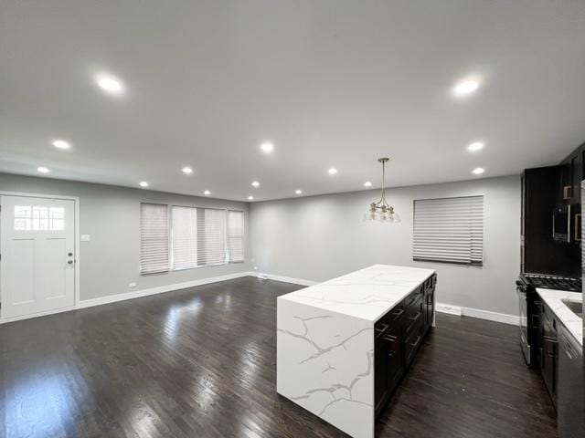 kitchen featuring stainless steel appliances, light stone countertops, dark wood-type flooring, and pendant lighting