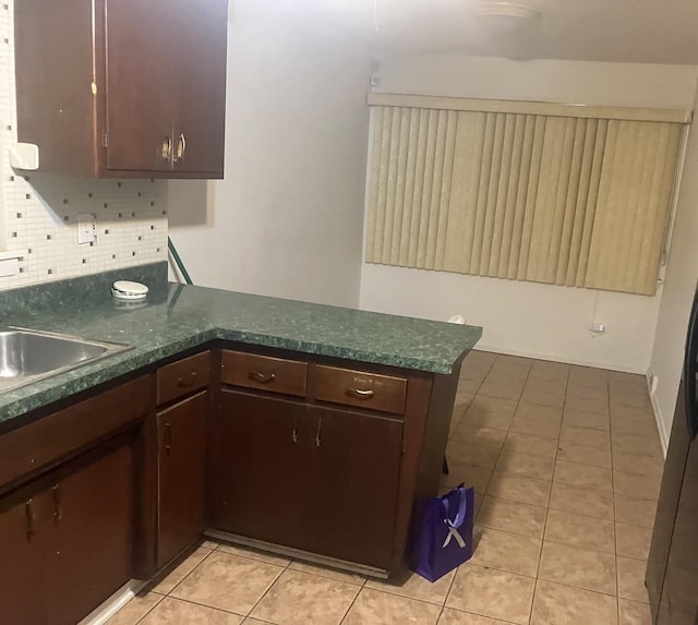 kitchen featuring cream cabinets, sink, decorative backsplash, light tile patterned floors, and kitchen peninsula