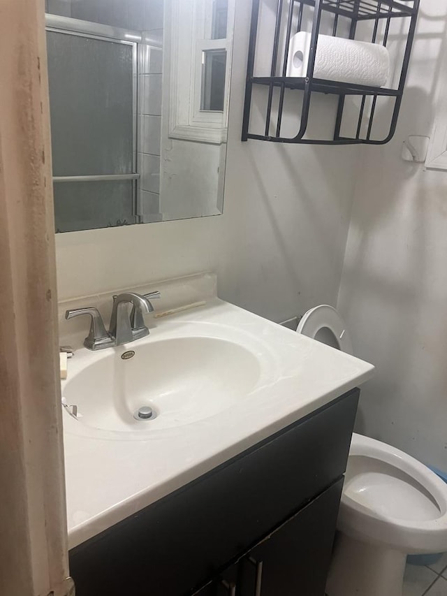 bathroom featuring a shower with door, vanity, and toilet