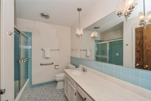 full bathroom with toilet, shower / bath combination with glass door, vanity, tile patterned flooring, and decorative backsplash