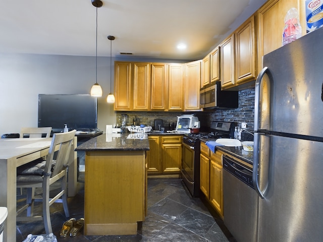 kitchen with decorative backsplash, stainless steel appliances, dark stone countertops, a center island, and hanging light fixtures