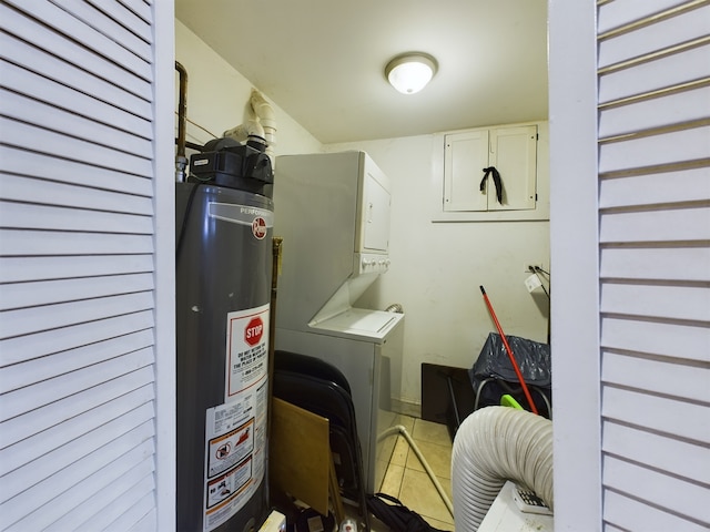 laundry area with gas water heater, stacked washer / drying machine, and light tile patterned flooring