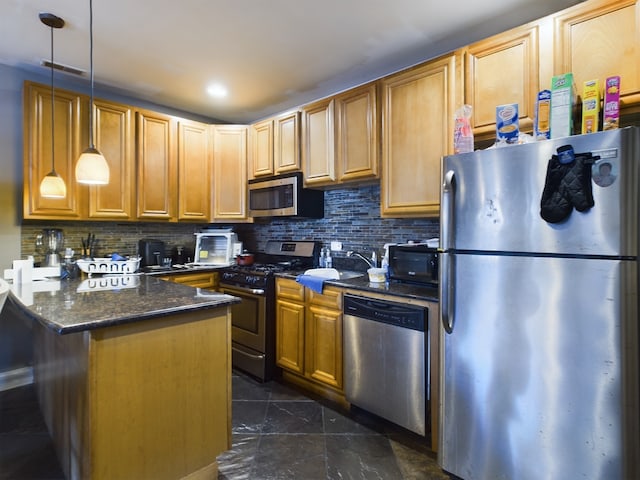 kitchen with appliances with stainless steel finishes, tasteful backsplash, sink, dark stone countertops, and hanging light fixtures