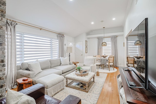 living room featuring ornamental molding, vaulted ceiling, plenty of natural light, and wood finished floors