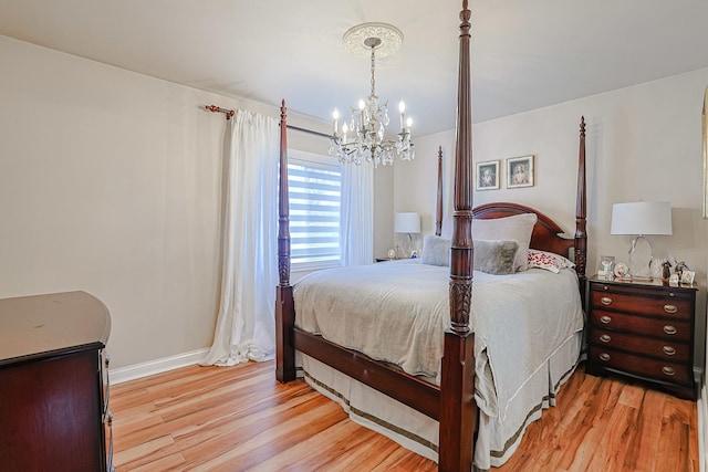 bedroom featuring baseboards, light wood finished floors, and an inviting chandelier