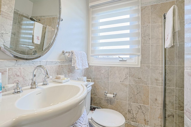 full bathroom featuring toilet, tile walls, a sink, and tiled shower