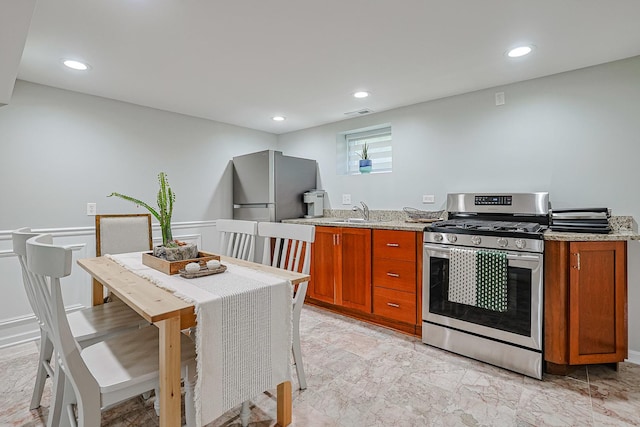 kitchen featuring appliances with stainless steel finishes, recessed lighting, a sink, and light stone countertops