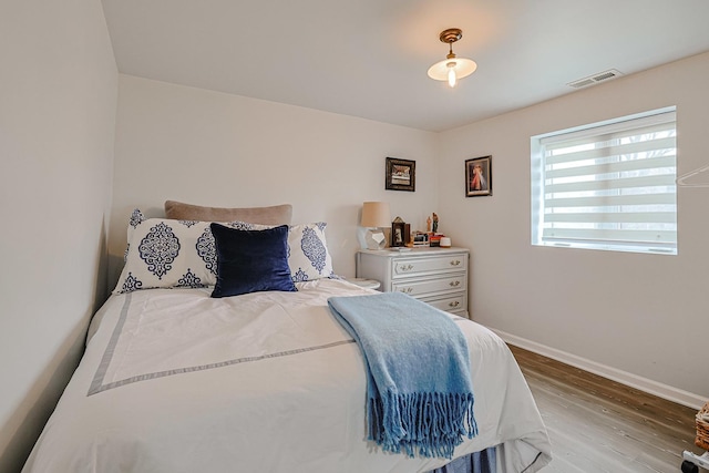 bedroom with visible vents, baseboards, and wood finished floors