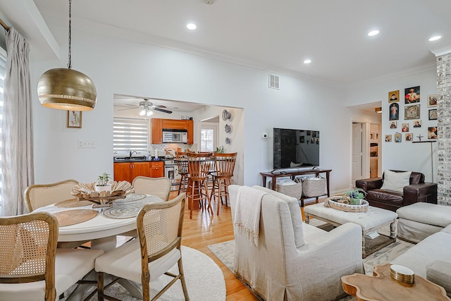 living area featuring recessed lighting, visible vents, ornamental molding, ceiling fan, and light wood-type flooring