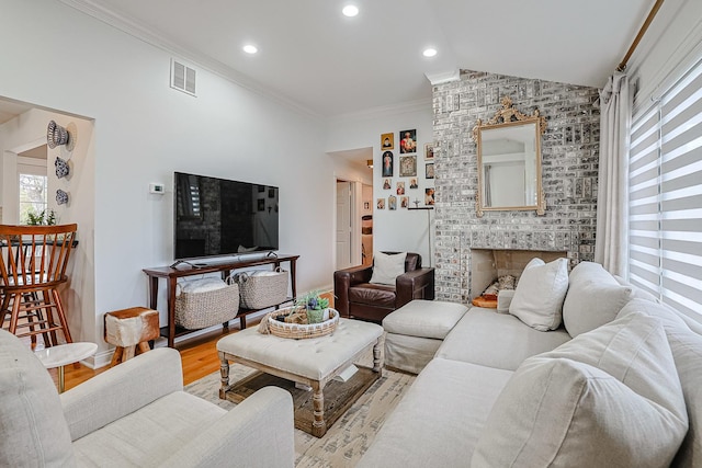 living room with light wood-style floors, visible vents, plenty of natural light, and ornamental molding