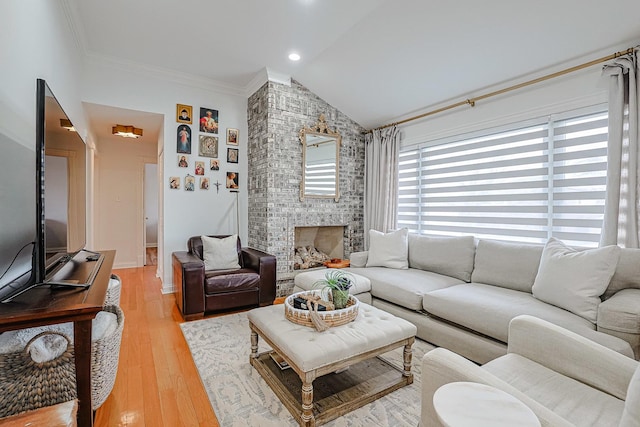 living room featuring lofted ceiling, a brick fireplace, ornamental molding, and wood finished floors