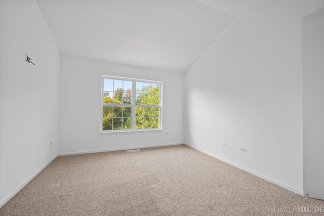 empty room with vaulted ceiling and carpet flooring