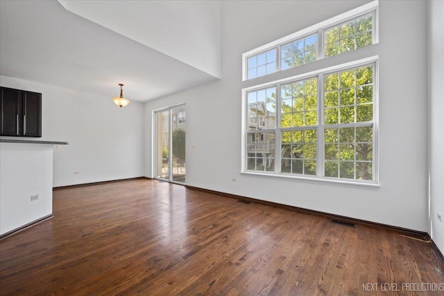 unfurnished living room featuring dark wood-type flooring and a high ceiling